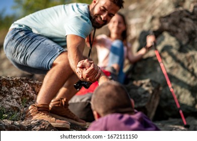 Young Man Help His Friend To Climb To The Top. Hiker Gives A Hand To Pull Up The On Mountain.