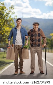 Young Man Helping A Senior Outdoors And Carrying Grocery Bags