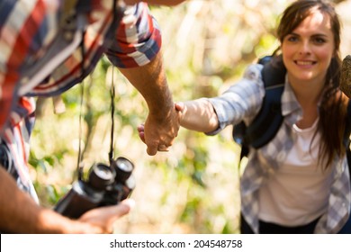 Young Man Helping Woman Climbing Mountain