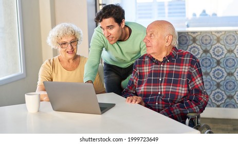 Young Man Helps Senior Couple On Laptop Computer With Video Call And Chat