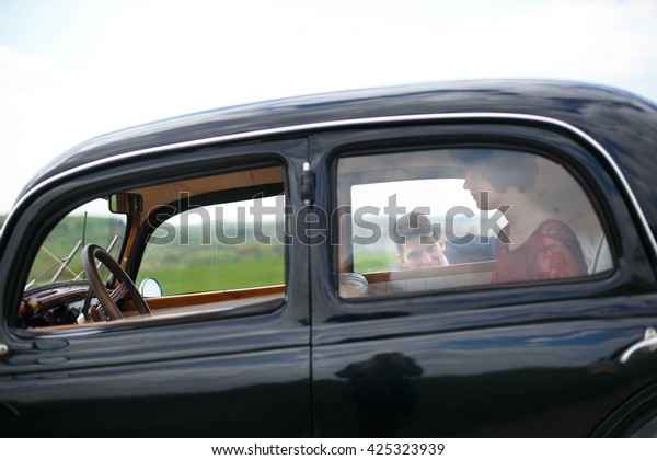Young man hides\
from the lady in vintage\
car
