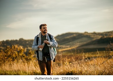 Young man hiker on a trail refreshing from a water bottle and looking aside. Shot of a man drinking water. People travel outdoor concept. Copy space - Powered by Shutterstock