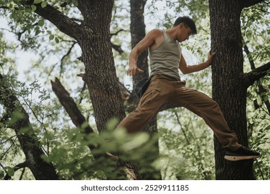 Young man hiking and climbing trees in a lush forest on a sunny summer day, enjoying adventure and exploration in nature. - Powered by Shutterstock