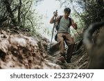 Young man hiking down a mountain trail through the forest, enjoying an adventurous and healthy lifestyle on a sunny summer day.