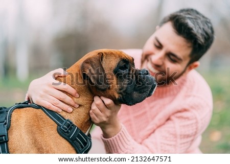 young man with his boxer dog in the park. focus on the dog
