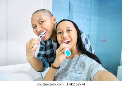 Young man and his daughter taking selfie picture together while brushing teeth in the bathroom. Shot at home - Powered by Shutterstock