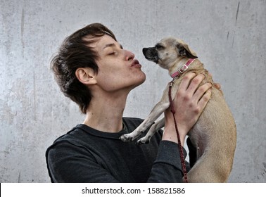 Young Man With His Dog In His Arms And Giving Kisses