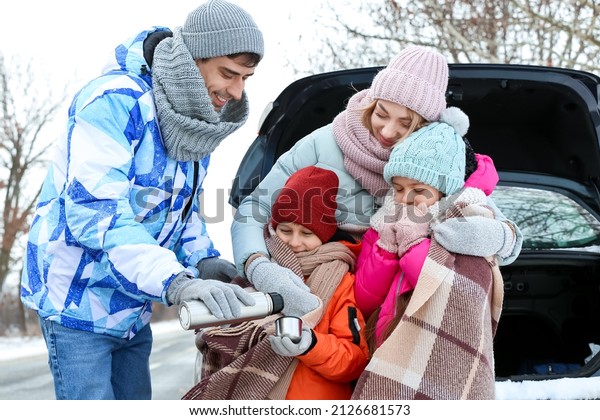 Young man with his family drinking hot tea on snowy\
winter day