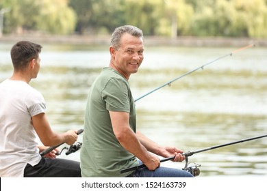 Young man and his father fishing on river - Powered by Shutterstock