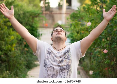 Young Man With His Hands Up In The Air, Facing The Sky.