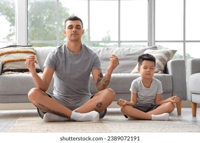 Young man with his little son meditating at home - Powered by Shutterstock