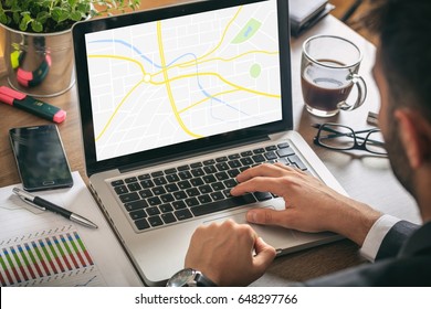 Young Man In His Office Looking At A Map On Laptop Screen