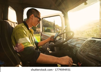 Young Man In His Truck Inside The Cabin With The Security Clothes Using The Smartphone