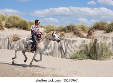 Young Man And His White Horse Galloping On The Beach