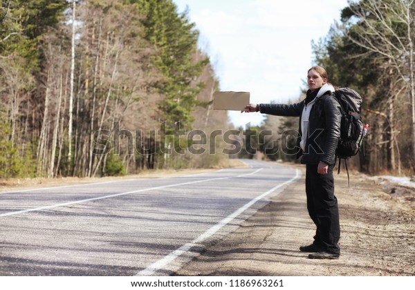 A young man is hitchhiking around
the country. The man is trying to catch a passing car for
traveling. The man with the backpack went hitchhiking to
south.
