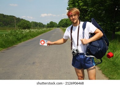 Young man is hitchhiking in the middle of nowhere in eighties.