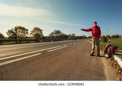 Young Man Hitchhiking On A Road