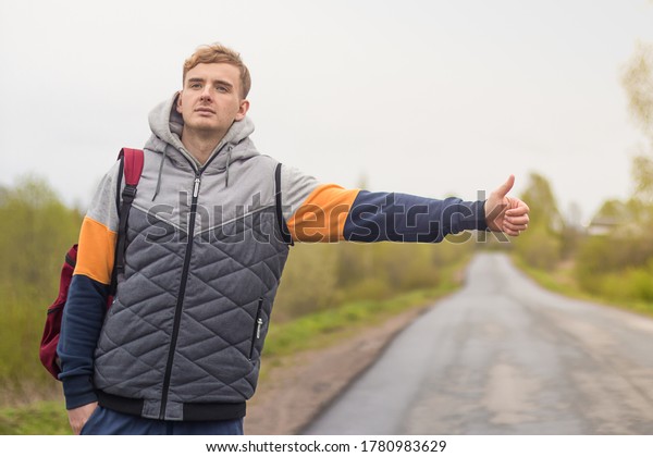 young man hitchhiking.\
passenger on the road near the curb. guy catches a taxi cab with\
thumb up gesture.