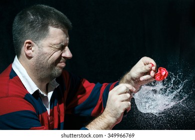 Young Man Hits A Coloured Water Baloon With A Needle And Make A Big Splash