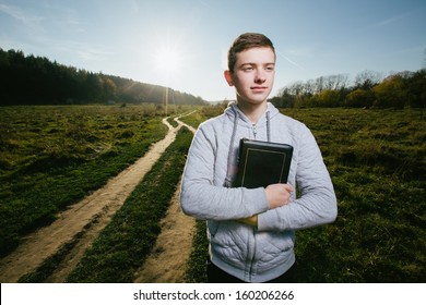 Young Man Holding Bible In A Park