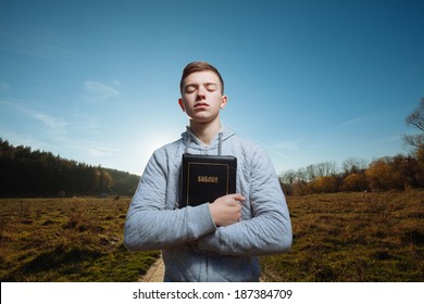 Young Man Holding Bible In A Park