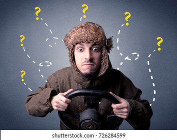 Young man holding black steering wheel with question marks around him - Shutterstock ID 726284599