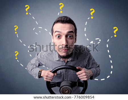 Young man holding black steering wheel with question marks around him