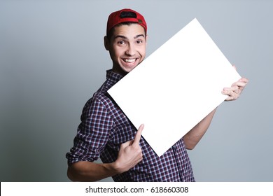 Young Man Holding A Blank Paper In A Studio