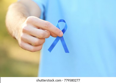 Young man holding blue ribbon outdoors, closeup. Prostate cancer awareness concept - Shutterstock ID 779580277