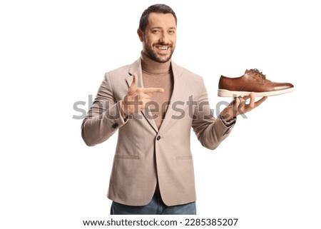 Young man holding a brown leather shoe and pointing isolated on white background