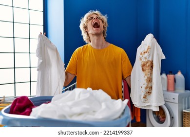 Young Man Holding Clean White T Shirt And T Shirt With Dirty Stain Angry And Mad Screaming Frustrated And Furious, Shouting With Anger Looking Up. 