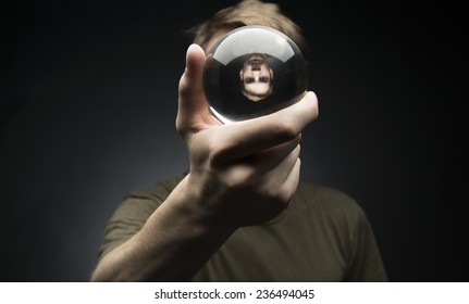 Young Man Holding A Clear Transparent Crystal Glass Ball In Their Hand