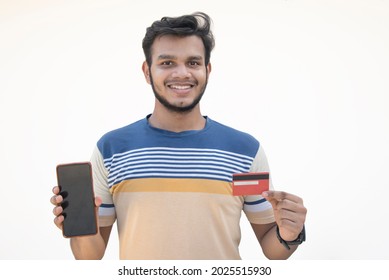 A Young Man Holding A Credit Card And Mobile Phone In Hand