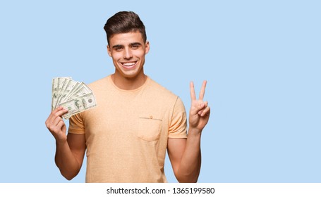 Young man holding dollars doing a gesture of victory