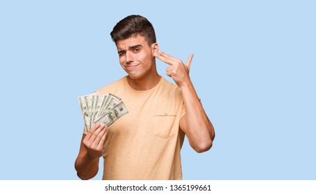 Young man holding dollars doing a suicide gesture