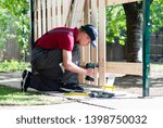 Young man holding drill-drive while screwing screw 