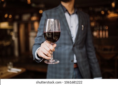 A Young Man Holding A Glass Of Red Wine