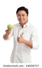 Young man holding a green apple, doing thumbs up. Wearing a white shirt. White background.