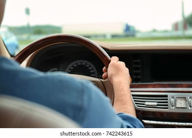 Young man holding hand on steering wheel of car - Shutterstock ID 742243615