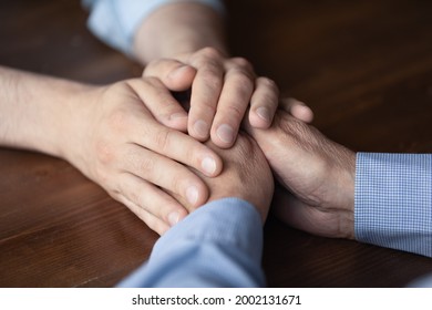 Young Man Holding Hands Of Elderly Father Close Up. Grown Son Giving Comfort And Support To Senior Father At Moment Of Stress, Grief, Despair, Disease. Family, Empathy Concept. Cropped Shot