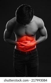 Young Man Holding His Sick Stomach In Pain On Black Background