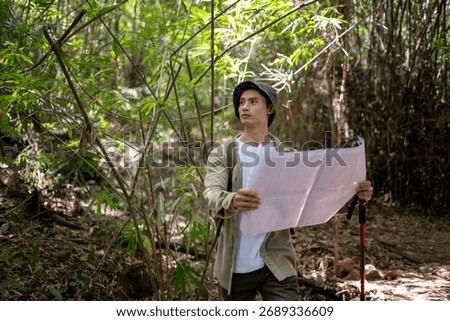 Young man holding map while hiking through a green bamboo forest