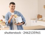 Young man holding modern toaster with crispy toasts in kitchen