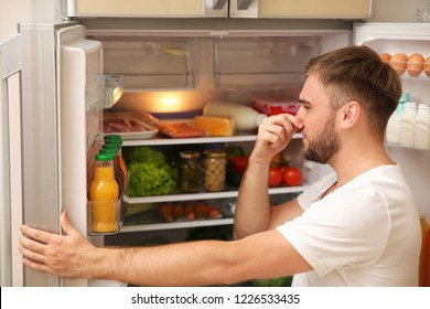 Young Man Holding Nose Cause Of Bad Smell In Refrigerator At Home