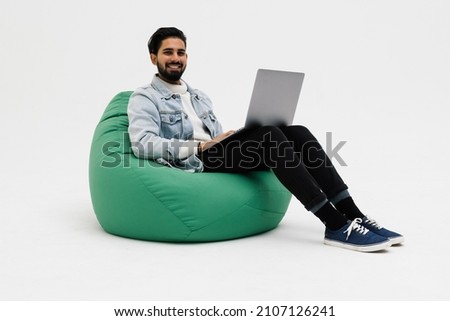 Young man holding notebook browsing chatting colleagues sitting comfy soft armchair wear specs casual denim outfit isolated on white background