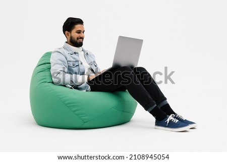 Young man holding notebook browsing chatting colleagues sitting comfy soft armchair wear specs casual denim outfit isolated on white background