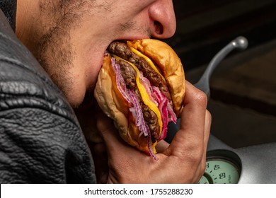 Young Man Holding A Piece Of Hamburger. Eats Fast Food. Burger Is Not Helpful Food. Very Hungry Guy. Diet Concept.