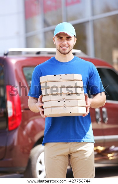 Young man holding pizza\
outside