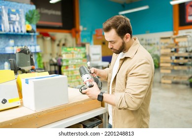 Young Man Holding A Power Tool At The Hardware Store And Shopping For A New Polisher For His Woodwork Projects
