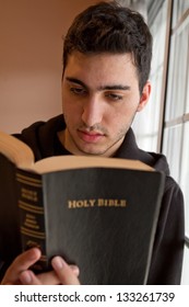 Young Man Holding And Reading A Bible